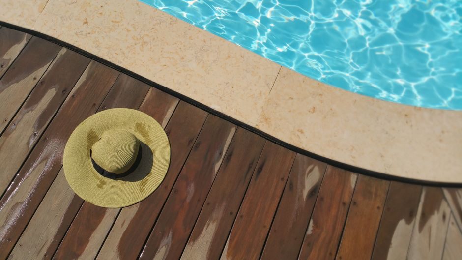 Margelles en pierre et plage en bois autour d'une piscine