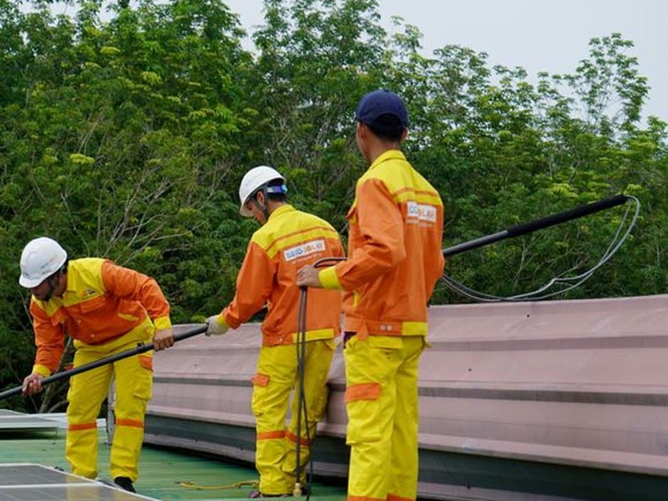 Techniciens utilisant des perches télescopiques à eau pure, sans brosse, pour rincer des panneaux photovoltaïques