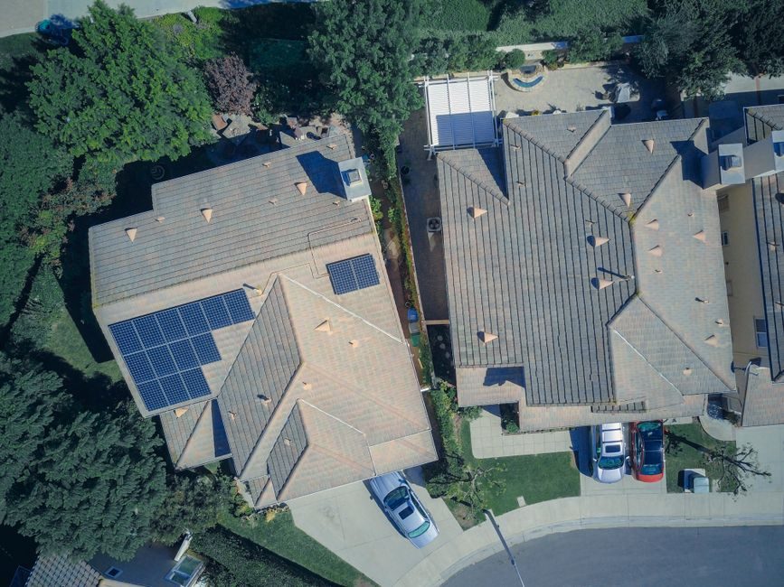 Vue aérienne de maisons avec toitures, panneaux solaires et abords extérieurs